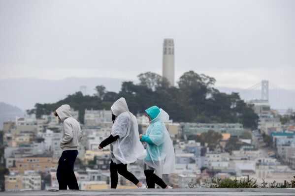 Visitors take in city views at Hyde and Lombard streets as rain begins to soak the Bay Area, in San Francisco, Sunday, Feb. 15, 2026. (Brontë Wittpenn/San Francisco Chronicle via AP)